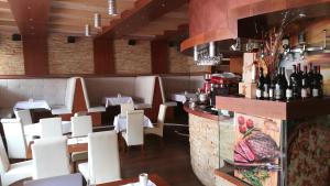 a restaurant with a bar with white chairs and wine bottles at Apartment Unna in Kopaonik
