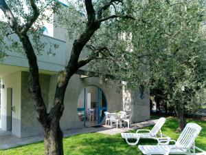 Casa Sandra Bertolini Alla Spiaggia في ناجو توربولي: مجموعة من الكراسي البيضاء وطاولة تحت شجرة