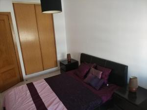 クアルテイラにあるAustral Apartmentのベッドルーム1室(紫のシーツと枕が備わるベッド1台付)