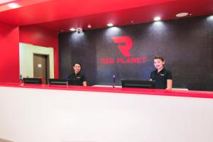 two people standing at a red planner sign in a room at Red Planet Cagayan De Oro in Cagayan de Oro