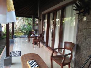 a porch with chairs and a table with a chess board at Dedik House in Ubud