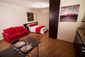NewCity Hotel & Suites في القاهرة: غرفة معيشة مع أريكة حمراء وسرير