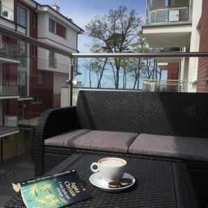 eine Tasse Kaffee und ein Buch auf dem Tisch auf dem Balkon in der Unterkunft Apartament przy Plaży / Klifowa in Rewal