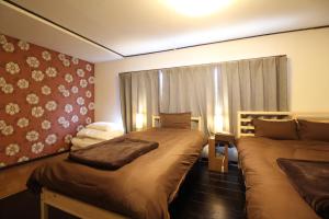 a bedroom with two beds and a window at LiB PLUS Kyoto Maiko Han-inn in Kyoto