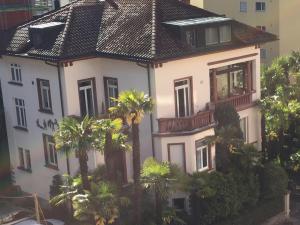 a white house with palm trees in front of it at Paracelsus Locarno Stadt Wohnung in Locarno