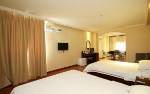 a hotel room with two beds and a television at GreenTree Inn Hainan Haikou Guomao Business Hotel in Haikou