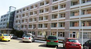 a parking lot with cars parked in front of a building at Hotel Ovidiu in Mamaia