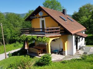 une petite maison jaune et blanche avec une terrasse couverte dans l'établissement Kuća Juraj, à Brod na Kupi