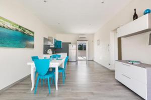 una cucina e una sala da pranzo con tavolo bianco e sedie blu di Villa Evi by BarbarHouse a Specchiolla