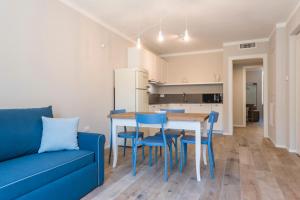 salon z niebieską kanapą, stołem i krzesłami w obiekcie Casa Tonetta Luxury Apartments w Arco
