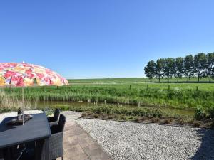 een tafel met een parasol op een patio met een veld bij Modern Holiday Home in Ooltgensplaat in Ooltgensplaat