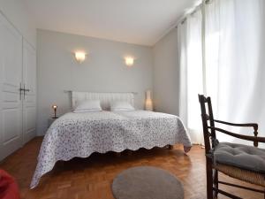 a white bedroom with a bed and a chair at Apartment with south facing balcony in Yèvre-le-Châtel