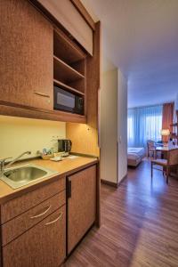 a kitchen with a sink and a living room at Hotel Residenz Limburgerhof in Limburgerhof