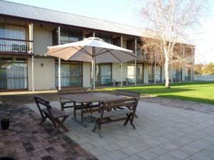 a patio with a table and chairs and a patio umbrella at Coonawarra Motor Lodge in Penola