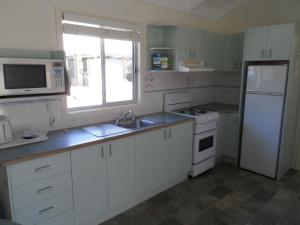 a kitchen with a refrigerator, stove, microwave and sink at Lakesea Park in Durras
