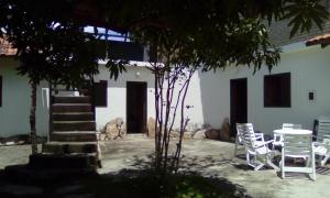 eine Gruppe weißer Stühle, ein Tisch und ein Gebäude in der Unterkunft Pousada Chalés do Lago in Cavalcante