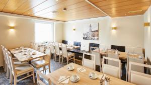 ein Restaurant mit Holzdecken, Tischen und Stühlen in der Unterkunft Hotel Imperial in München