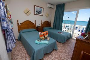 トレモリノスにあるHotel Mediterraneo Carihuelaのベッドルーム1室(ベッド2台付)、海を望むバルコニーが備わります。