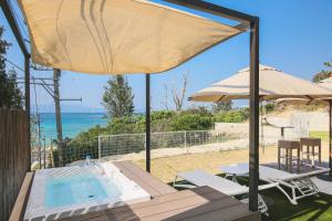 恩納的住宿－Hermit Hills Okinawa  -SEVEN Hotels and Resorts-，一个带桌子和遮阳伞的庭院和一个游泳池