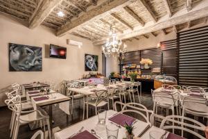 un ristorante con tavoli e sedie bianchi e un lampadario a braccio di Trevi Beau Boutique Hotel a Roma