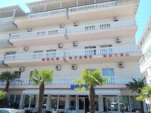 a building with palm trees in front of it at Gold Stern in Paralia Katerinis