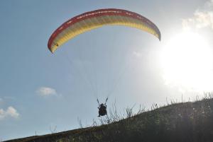 a person flying a parachute on a hill at Manuh Guest House in Nusa Dua
