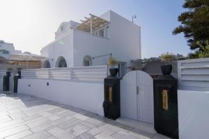 a white fence with a gate and a white building at Santorini Secret Suites & Spa, Small Luxury Hotels of the World in Oia