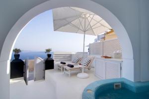 a patio with an umbrella and a swimming pool at Santorini Secret Suites & Spa, Small Luxury Hotels of the World in Oia