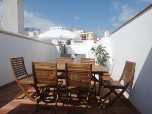 drewniany stół i krzesła na balkonie z parasolem w obiekcie Málaga Apartamentos - Jinetes, 10 w Maladze