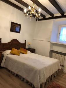 a bedroom with a large bed with a chandelier at Apartamentos La Casona in Ucieda de Arriba