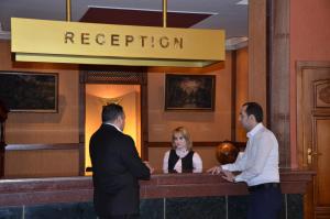 dwóch mężczyzn i kobieta stojąca przy recepcji w obiekcie Ganja Hotel w mieście Gandża