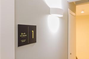 Un orologio su un muro con una luce sopra di Suite Bordonaro Apartments a Cefalù