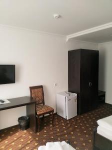 a room with a desk and a chair and a refrigerator at Аtria Hotel in Adler