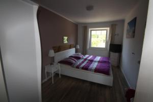 a bedroom with a white bed and white walls at Armarova Ihre Ferienpension in Cuxhaven