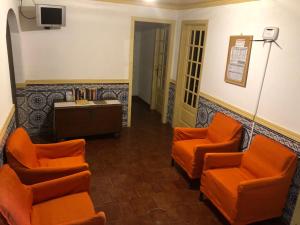 a waiting room with orange chairs and a tv at Olinda’s Rooms in Lagos
