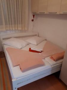 - un lit blanc avec des draps et des oreillers roses dans l'établissement Apartment Adriana, à Povljana