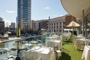 
a restaurant with tables, chairs and umbrellas at The Chelsea Harbour Hotel and Spa in London
