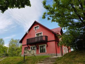 a red house with a balcony on a hill at Apartamenty u Bodzia in Stronie Śląskie