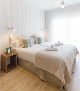 a white bedroom with a large bed with two towels on it at BYPILLOW Mumm in Vilanova i la Geltrú