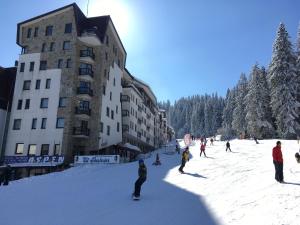 a group of people skiing in the snow in front of a building at Stenata Huge Ski To Door Apartment in Pamporovo