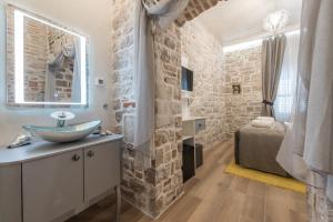 a bathroom with a stone wall and a sink at Zara Palace - design rooms in Zadar