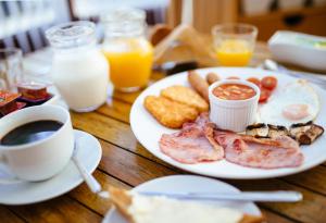 - une table avec une assiette de petit-déjeuner et une tasse de café dans l'établissement Pymgate Lodge Hotel Manchester Airport, à Cheadle