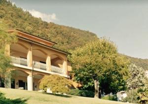 a large building with a tree in front of a mountain at Giuseppe B&B in Sarnico