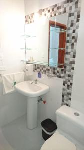 W łazience znajduje się umywalka, toaleta i lustro. w obiekcie Hotel Las Palmas w Esmeraldas
