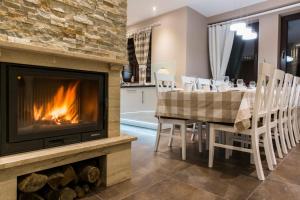 a living room with a fireplace and a table with chairs at Quality House - Cisza nad Doliną in Zakopane