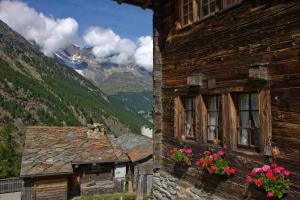 a building with flowers on the window and mountains at Hotel Olympia in Saas-Almagell