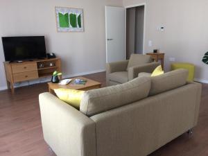 a living room with a couch and a tv at Domitys - Le Castel Du Val in Pérignat-lès-Sarliève