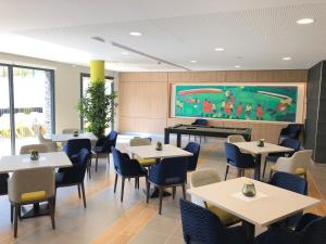 a dining room with tables and chairs and a large screen at Domitys - Le Castel Du Val in Pérignat-lès-Sarliève