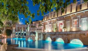 una piscina nel palazzo di Versailles di notte di The Ajit Bhawan - A Palace Resort a Jodhpur