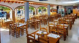 um restaurante com mesas e cadeiras de madeira e janelas em Camping Raco em Benidorm